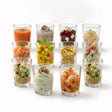 A set of twelve small glass containers holding assorted individual mini desserts and treats.