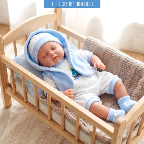 A doll sleeps in a crib, dressed in a light blue hooded onesie and matching blue booties.