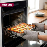 A person removes a hot stainless steel roasting tray filled with baked food from the oven.