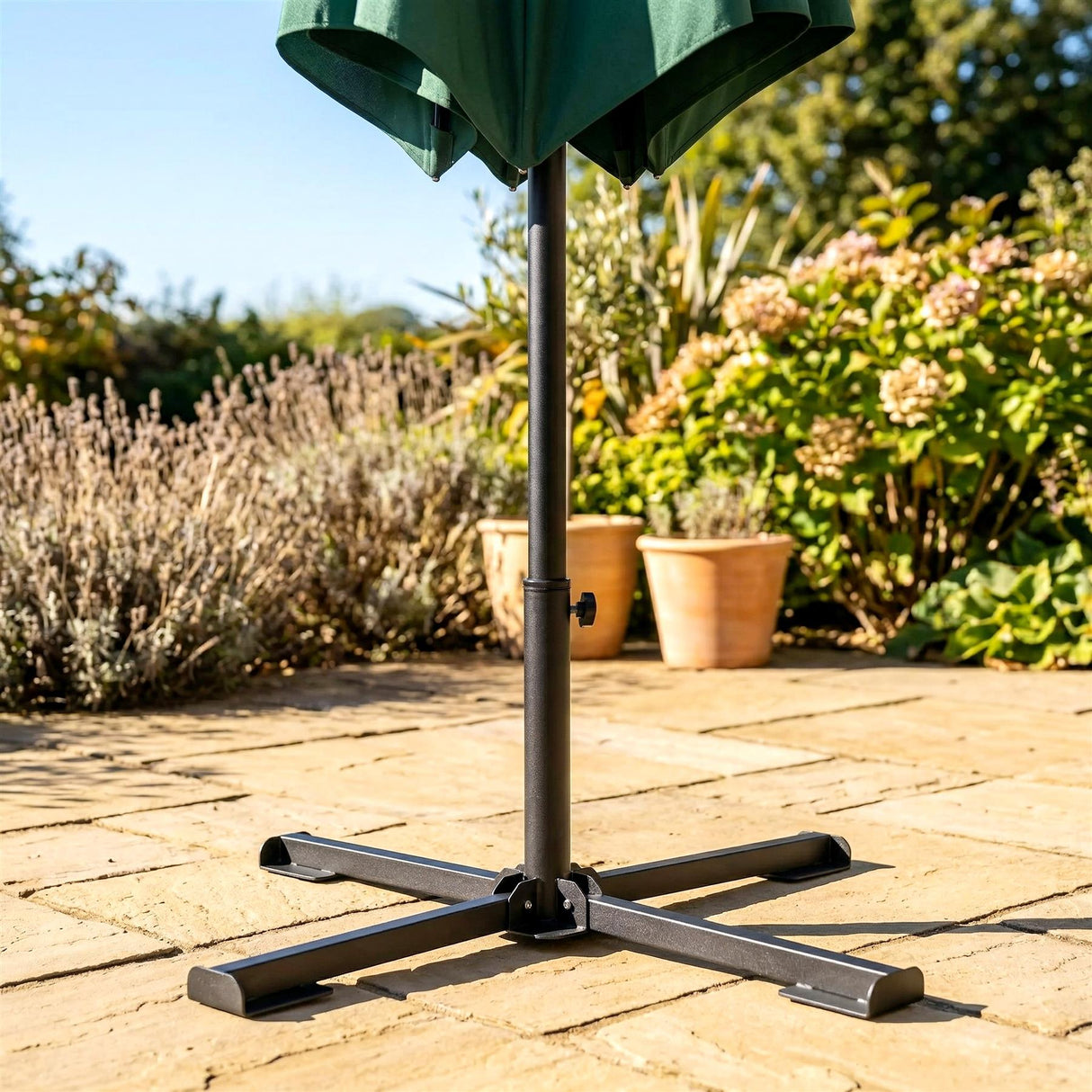 Dark metal foldable base with four legs stands on textured outdoor paving stones.