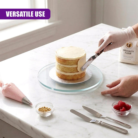 Glass turntable holding a layered cake, flour, and various baking tools on a counter.