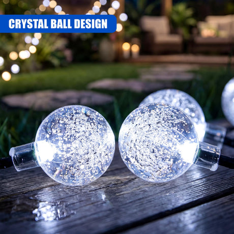 Glittery, spherical glass bulbs are strung across a rustic wooden surface outdoors.