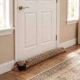 A brown dog draught excluder novelty rests on the wooden floor against a white interior door.