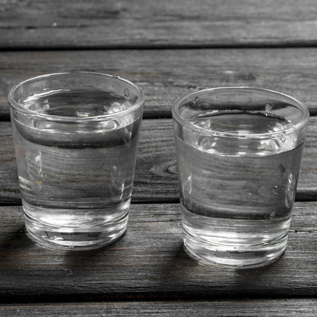 The image shows a set of three shot glasses on a wooden surface.