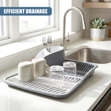 Rectangular drying rack holding two mugs, utensils, and two glasses on a kitchen counter.