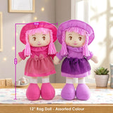 Two cloth rag dolls, one pink and one purple, standing together on a patterned surface.