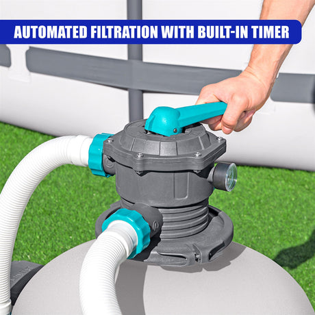 A hand adjusts the blue lever on a gray filtration unit connecting large white intake hoses.