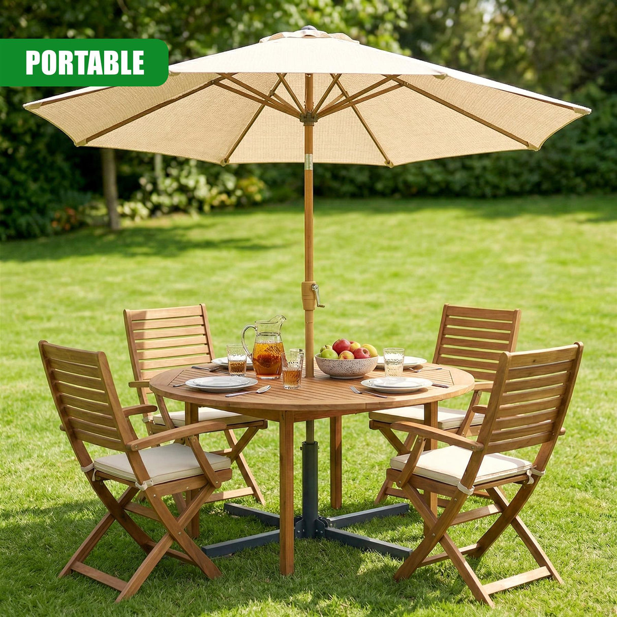 Outdoor setting with a round table, open umbrella, and four wooden folding chairs on green grass.