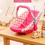 Pink and white patterned doll car seat with a handle placed on a light wooden table.
