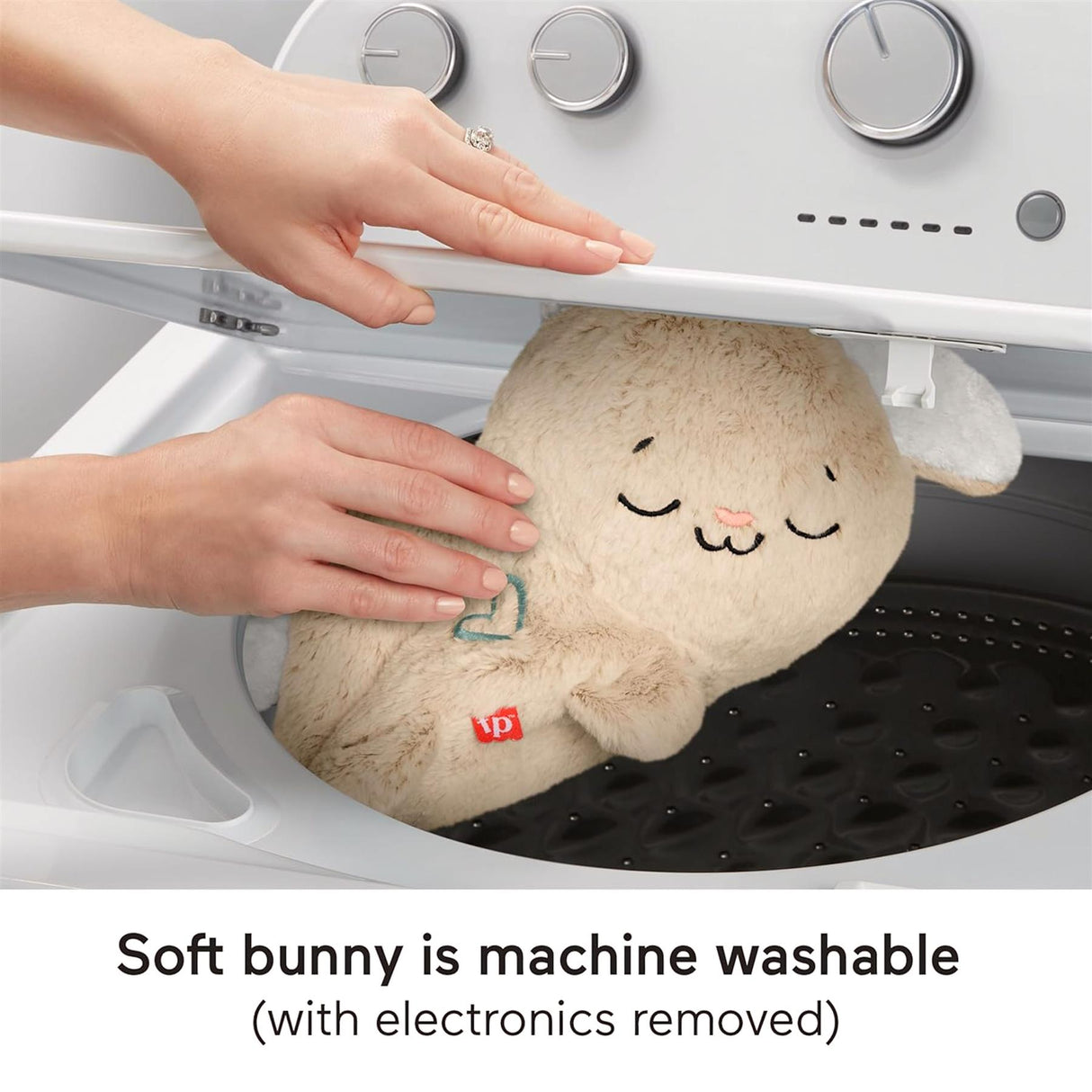 Hands handling a plush bunny toy inside the drum of a washing machine.