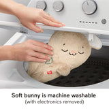 Hands handling a plush bunny toy inside the drum of a washing machine.