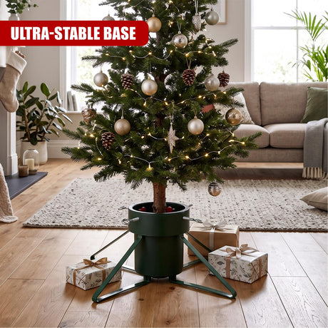 Green metal Christmas tree stand holding a decorated tree on wooden floor with presents nearby