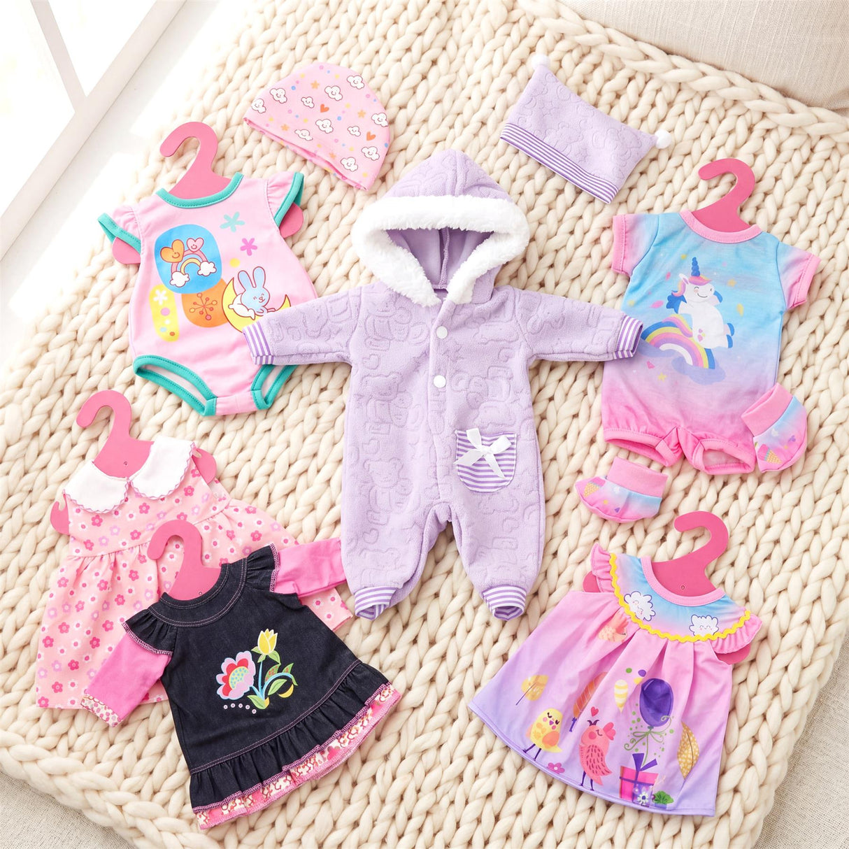 Set of doll clothes featuring pink, blue, purple, and floral patterns, including rompers, dresses, and a hooded sleeper.