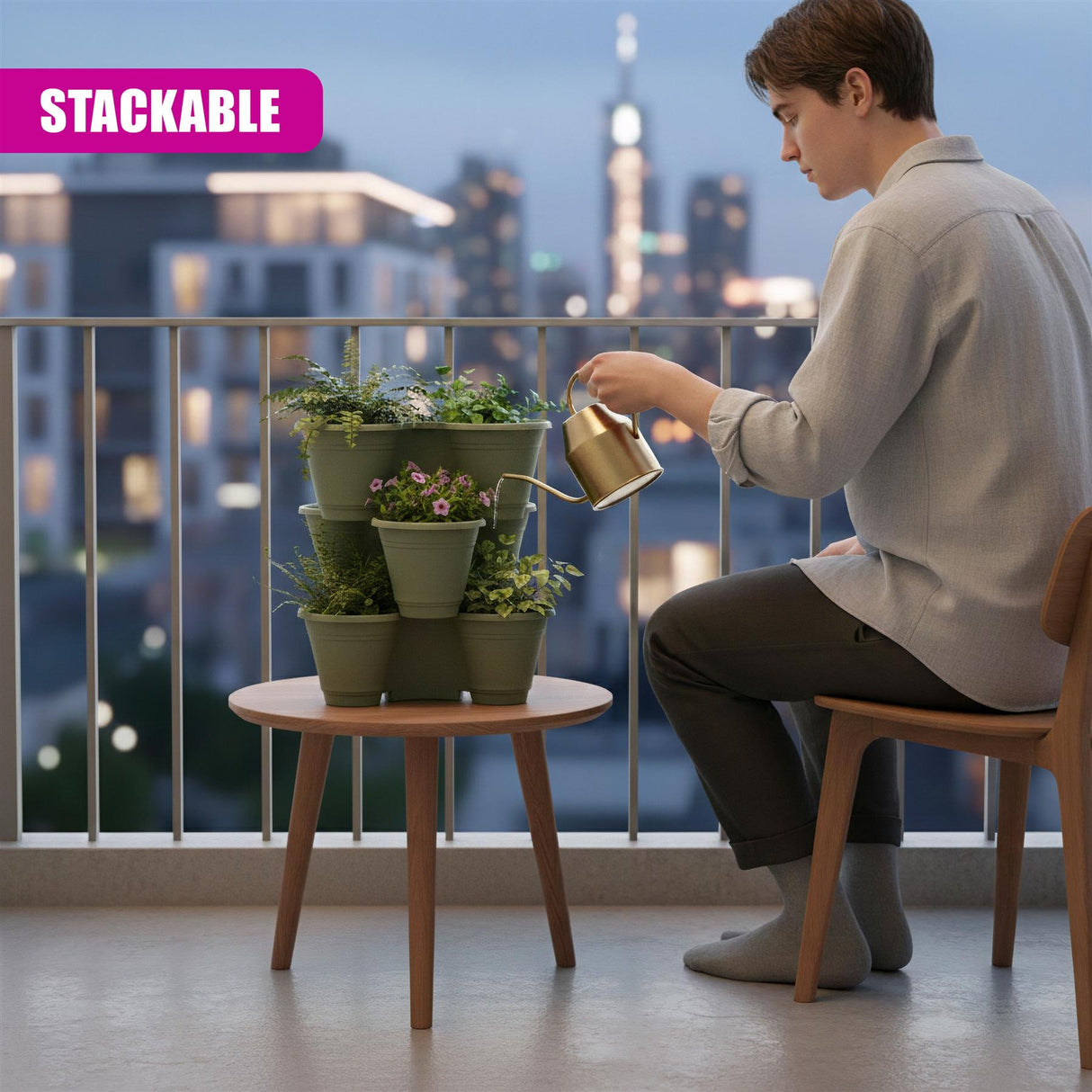 Stackable green planters holding potted flowers sit on a small wooden table outdoors.