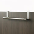 Silver metal rail with end brackets mounts horizontally on a dark wood surface for hanging towels.
