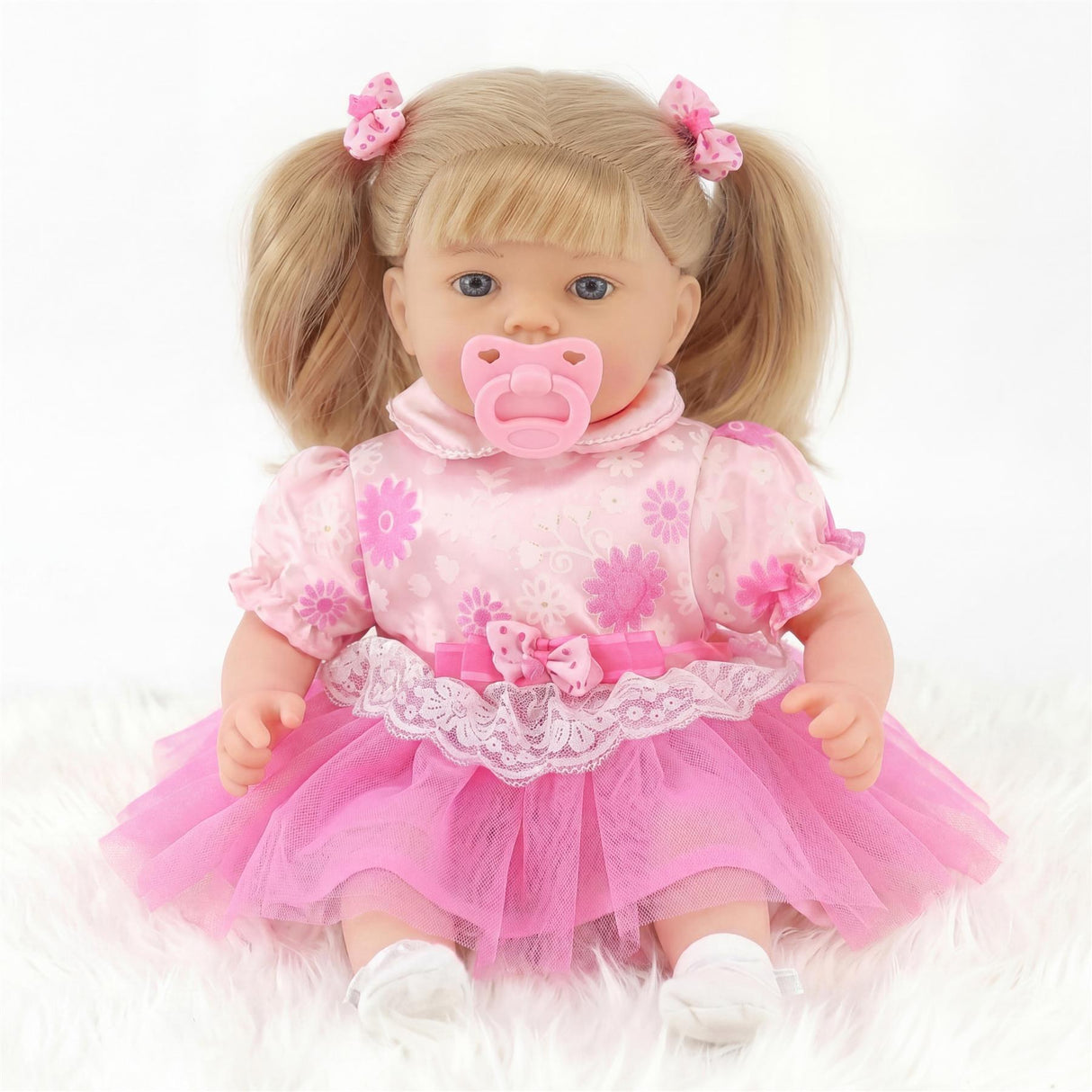 Blond doll with pigtails wearing a pink floral top, lace waistband, and layers of pink tulle skirt.