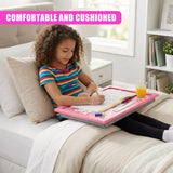Young girl writing on a pink lap tray set up on a bed.