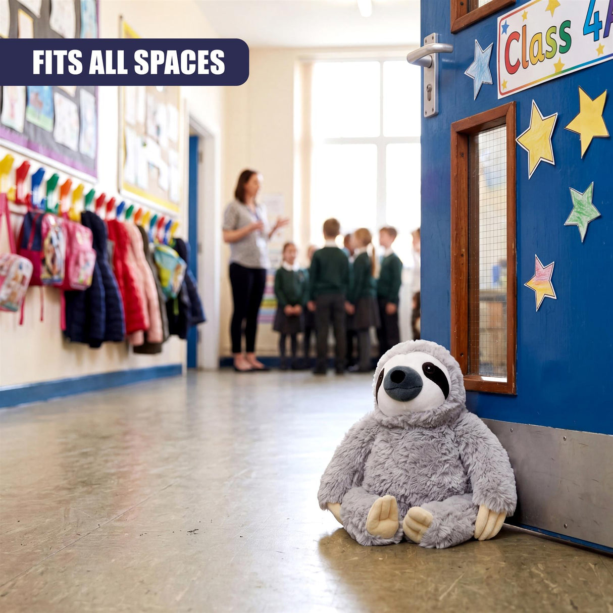 Gray stuffed sloth door stopper rests on the floor in front of a blue classroom door.