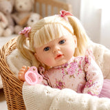 Large blonde baby doll with pink floral outfit and pacifier resting in a woven basket.
