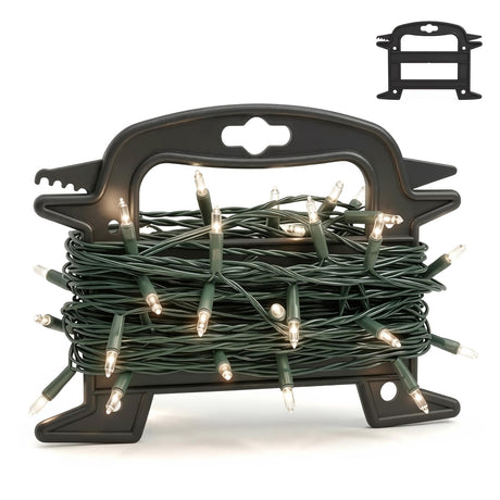 A black plastic Christmas light reel storage holder with a tangled green string of lit fairy lights coiled inside it