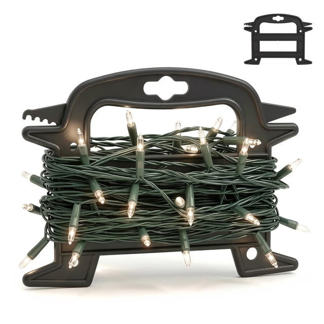 A black plastic Christmas light reel storage holder with a tangled green string of lit fairy lights coiled inside it