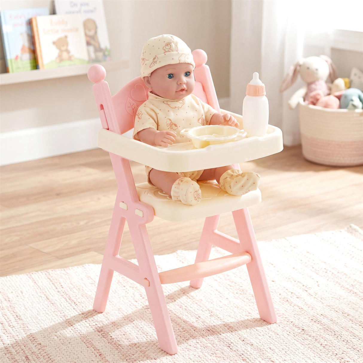 Baby doll sits in a pink high chair with a bowl and a baby bottle on the feeding tray.