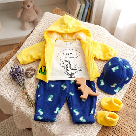 A yellow hooded set includes pants, white t-shirt, blue hat, yellow booties, and small dino toy accessory.