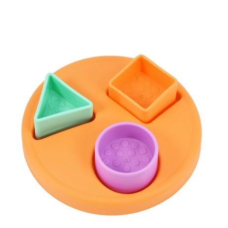 Three colored plastic shapes are attached to an orange base: a green triangle, orange square, and purple circle.