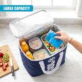 Open blue cooler bag holds prepared food, juice, and a cold pack; visible cutting board has fruit.