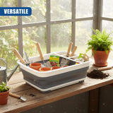 A gray collapsible dish drainer holds gardening tools, small pots, and potting soil on a wooden countertop.