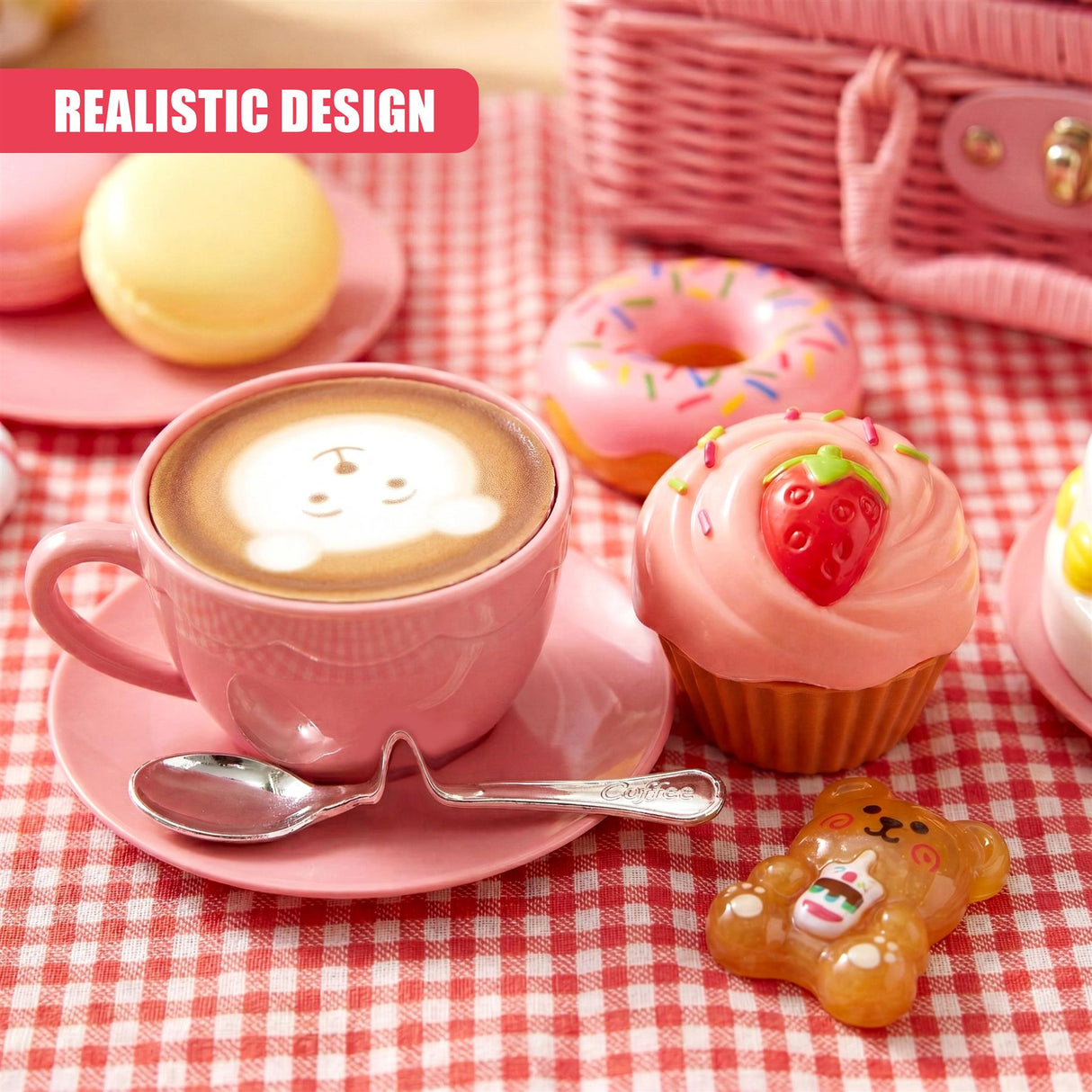 A teacup, macaron, strawberry cupcake, glazed donut, and bear candy on a picnic blanket.