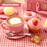 A teacup, macaron, strawberry cupcake, glazed donut, and bear candy on a picnic blanket.