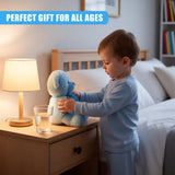 A young child in a bedroom, standing in front of a nightstand with a lamp, a glass of water, and a stuffed animal. The child is holding the stuffed animal, a soft blue bear, and is dressed in light blue pajamas. The room is dimly lit, with a soft glow from the lamp, and a bed with white sheets and pillows in the background. - UKBuyZone