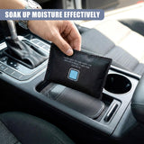 Hand placing a black, rectangular dehumidifier bag into the vehicle's cup holder.