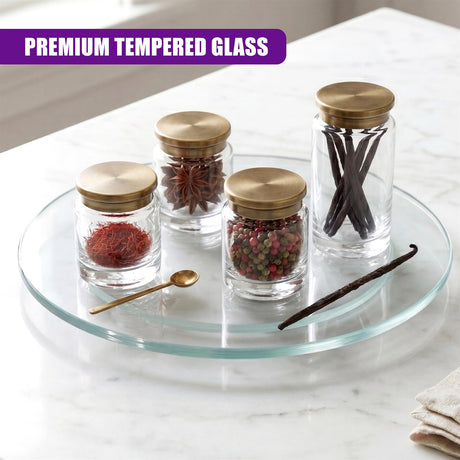 Clear glass turntable holding three spice jars, a small spoon, and cinnamon sticks.