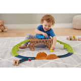 Young child interacts with a cargo train set featuring a wooden bridge and curving track.