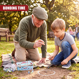 Older man and young boy kneeling outdoors near a blue and white tin box containing 160 marbles.