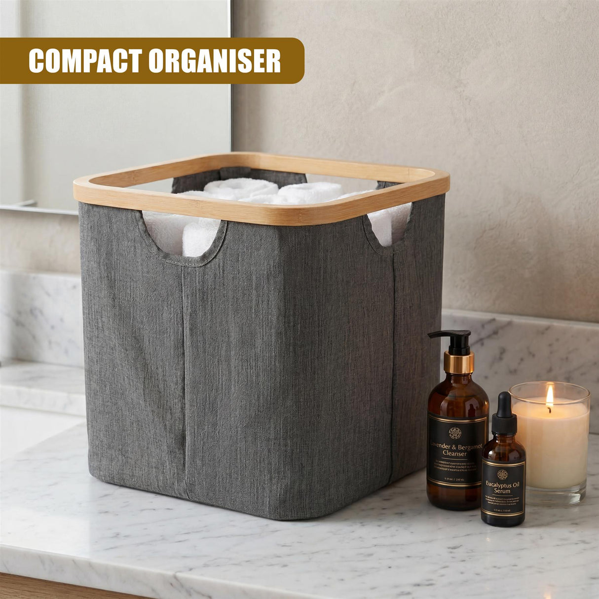 Gray fabric basket with wood trim rests on marble counter near soap bottles and candle.