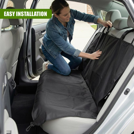 Woman installing a dark gray universal car seat cover inside a vehicle.
