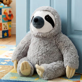 Plush gray sloth door stopper resting on a patterned rug against a light blue door.