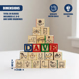 Stacked wooden blocks display letters, numbers, and engraved drawings of objects and animals.