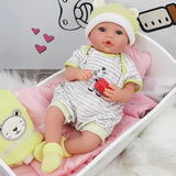 A baby doll wearing stripes and a hat rests in a pink wooden cradle with a yellow toy.