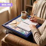 A person sits in a comfortable chair, holding a pen and writing in a planner. On the tray in front of them, a planner, pen, and a cup of tea are placed. The tray is designed with a tray table that can be adjusted to various heights, making it a versatile and practical addition to any home or office. - UKBuyZone