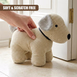 Crocheted light tan dog figure with black nose and gray ears placed near a white door.