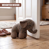 Tartan stuffed elephant door stopper resting against a white wooden door jamb.