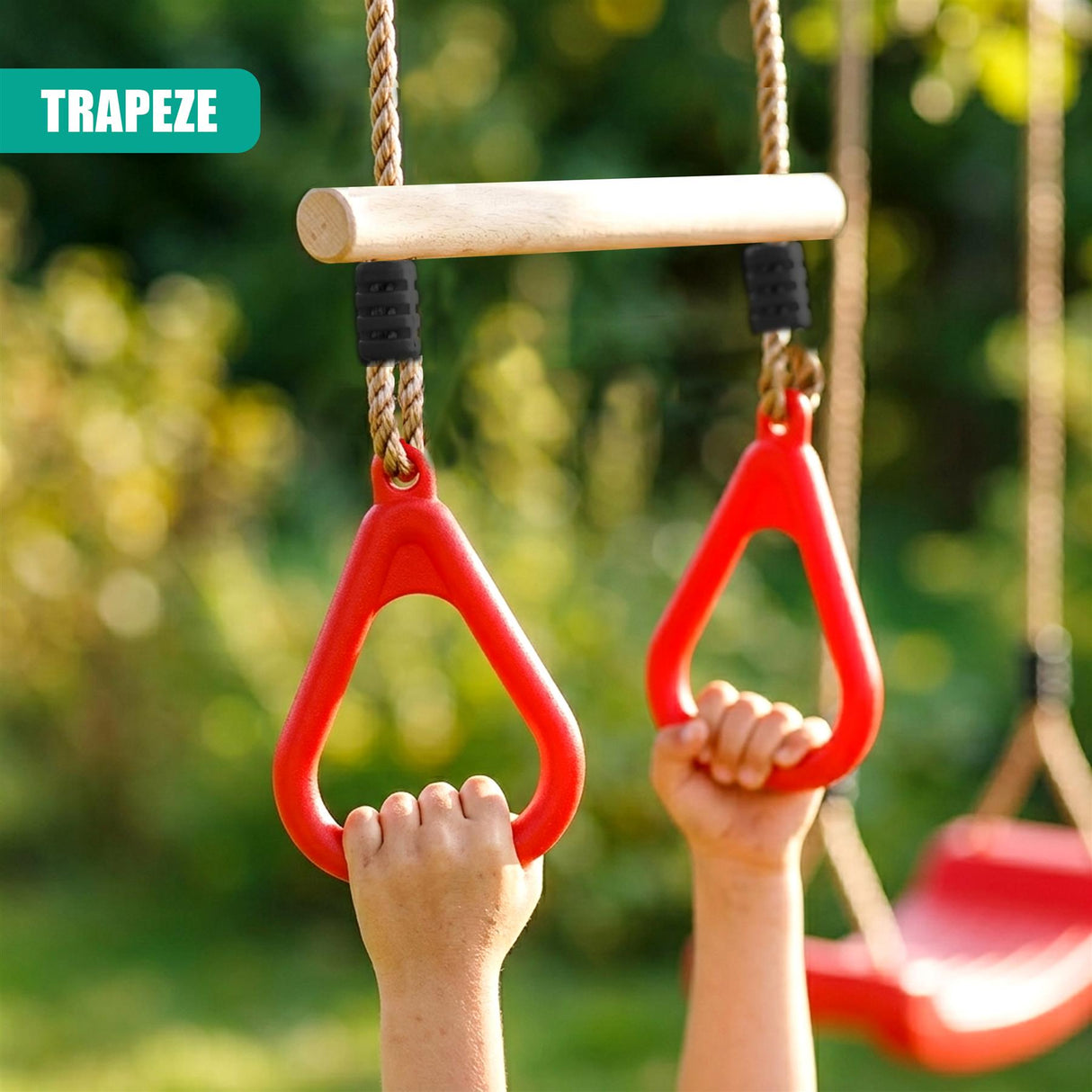 Two children hang from a red trapeze bar attached to a garden swing.