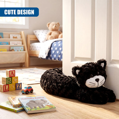 A black, plush cat draft stopper rests on a light wooden floor near a white door.