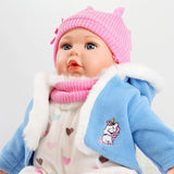 Baby doll wearing blue coat with fur hood and pink hat.