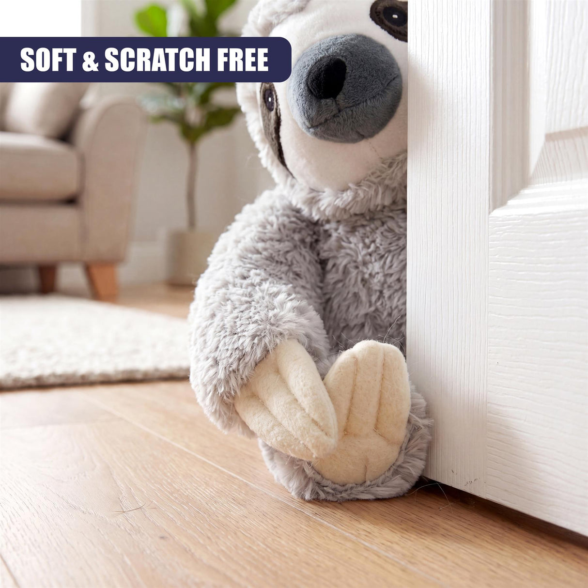 Plush gray sloth door stopper positioned leaning against a white interior door frame.