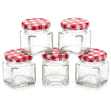 Five small, cubic glass jars are displayed with coordinating red and white checkered lids.
